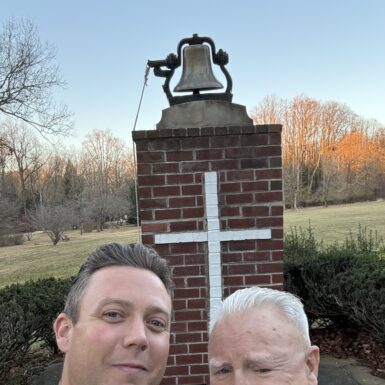 Frank Williams and His Father in front of the bell by St Joseph's Hall.