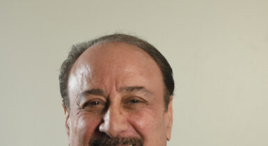 headshot of director, Paul Colletti, dressed in a suit and tie